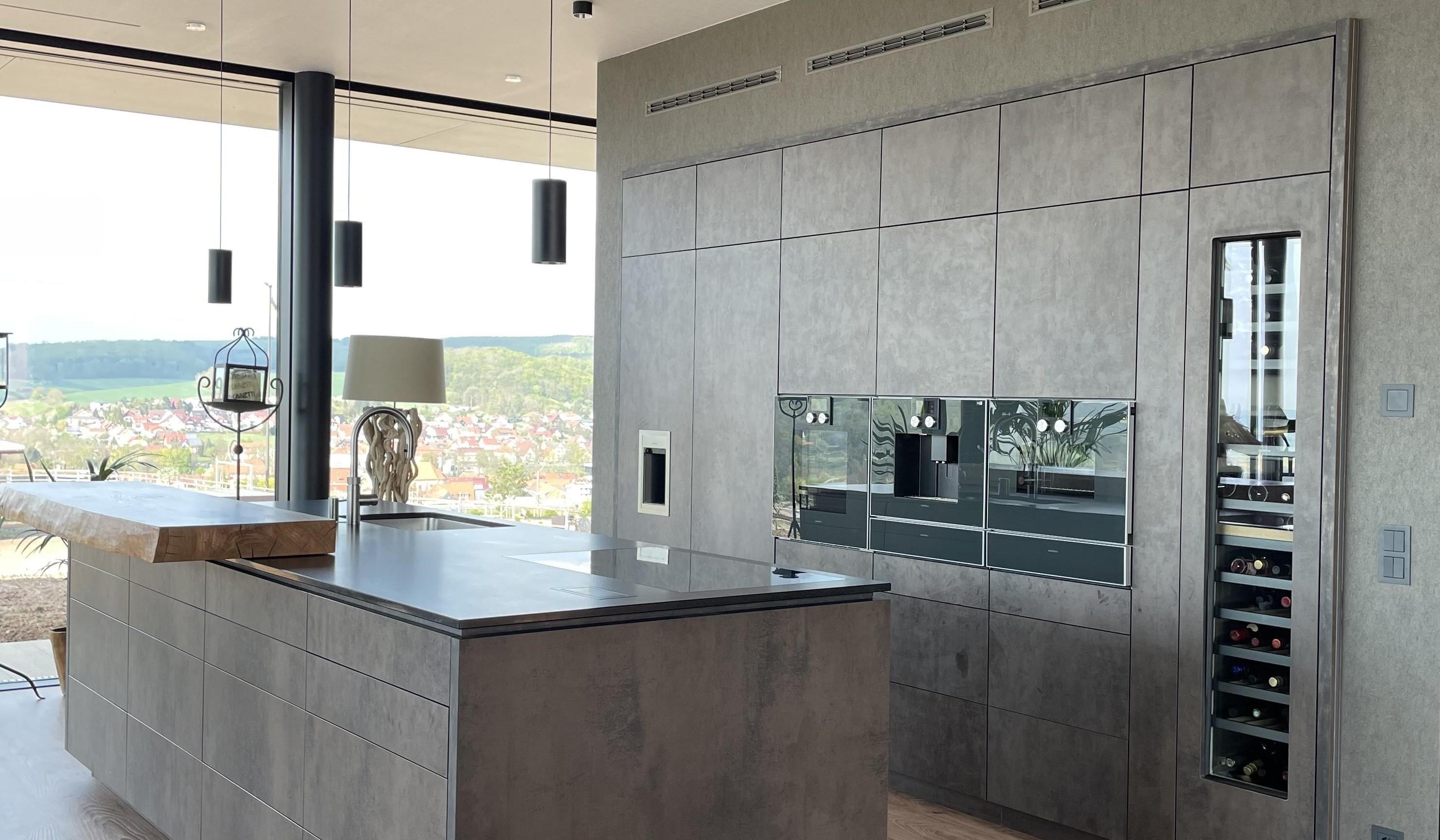 Moderne Küche mit Kochinsel, grauen Schränken und großem Fenster mit Aussicht.