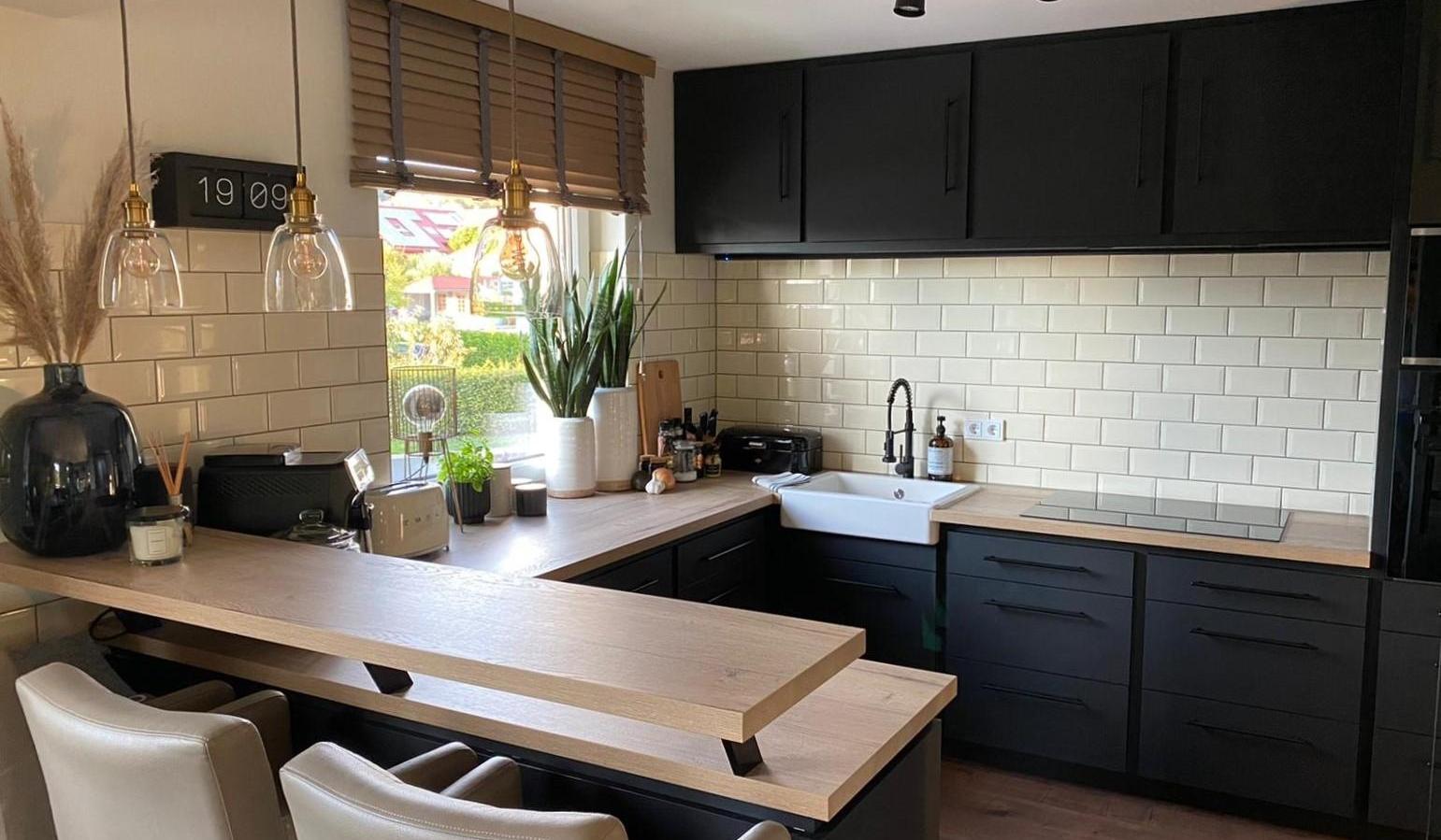 Moderne Küche mit schwarzen Schränken, Holzarbeitsplatte und weißen Fliesen.