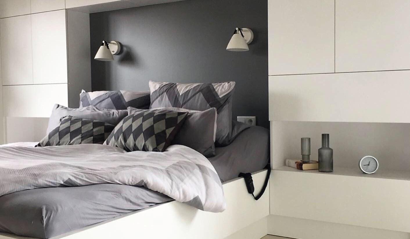 Bett mit Schrankwand dahinter, die viel Stauraum bietet. 