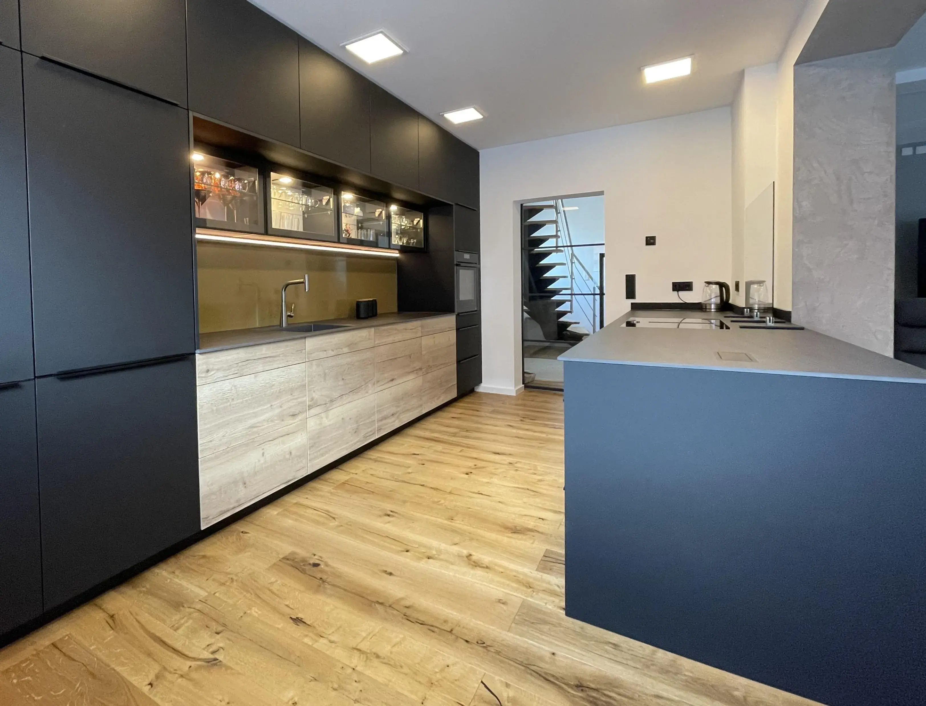 Moderne Küche mit dunklen Schränken, Holzfußboden und Kochinsel.