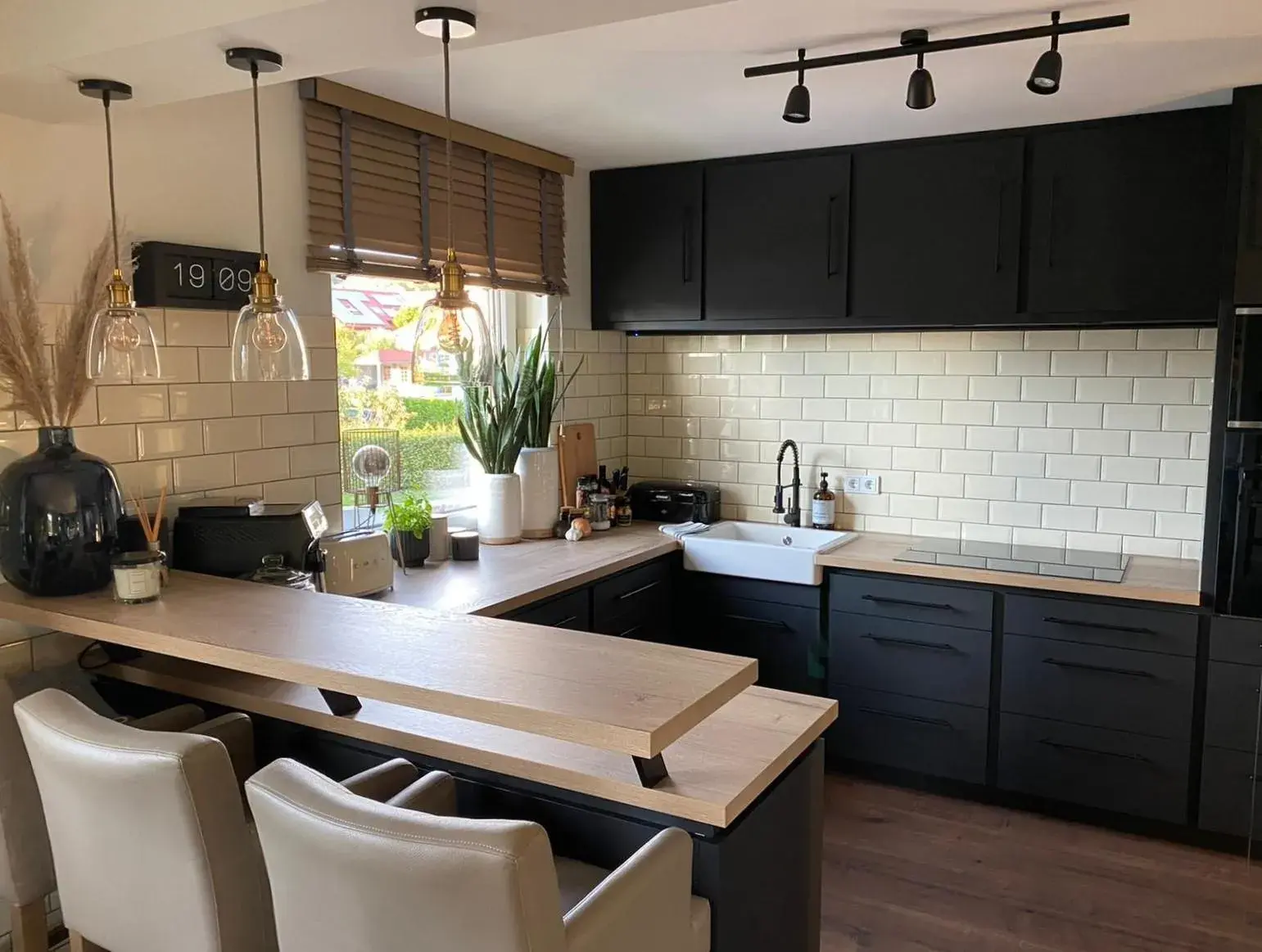 Moderne Küche mit schwarzen Schränken, Holzarbeitsplatte und weißen Fliesen.