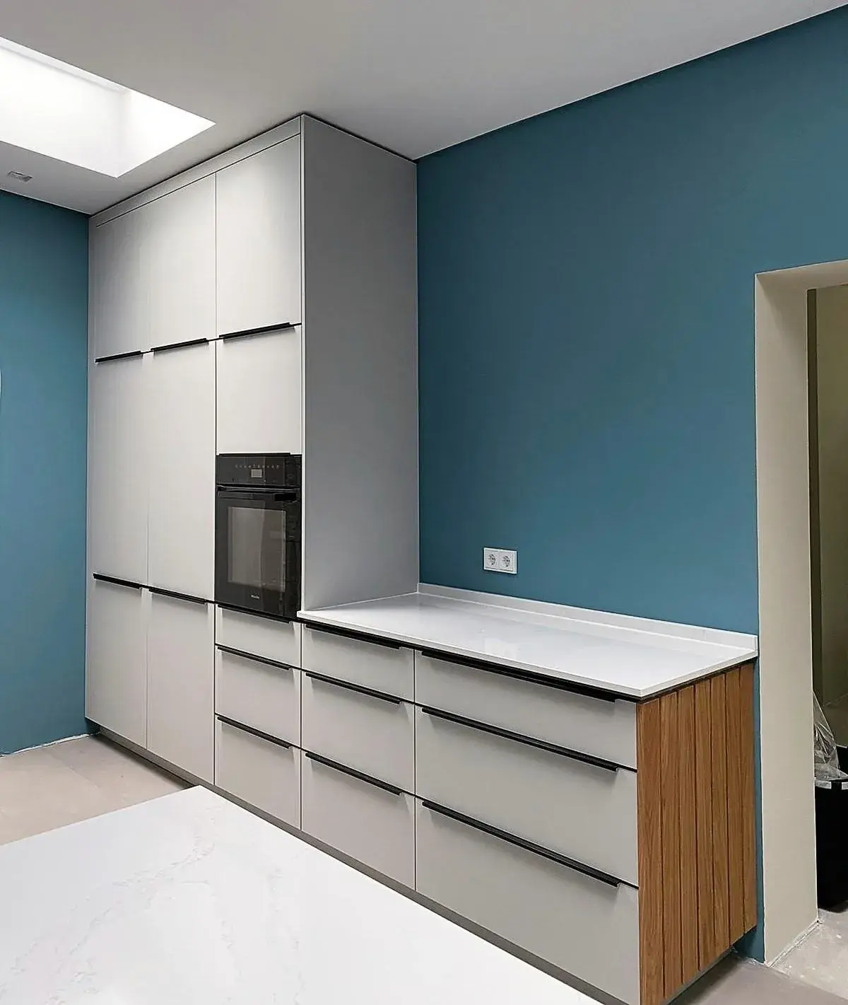 Moderne Küche mit blauen Wänden, weißen Schränken und Einbauofen